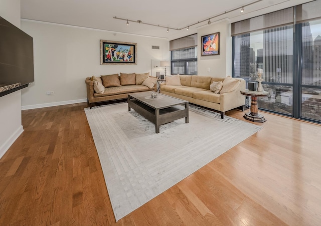 living room featuring track lighting, visible vents, baseboards, and wood finished floors