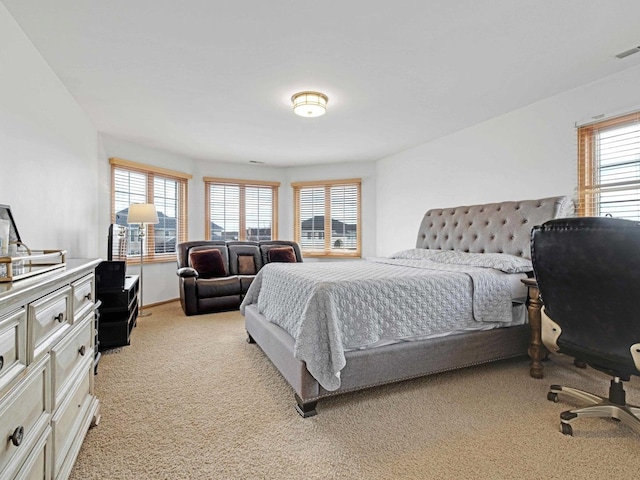 bedroom featuring light carpet and multiple windows