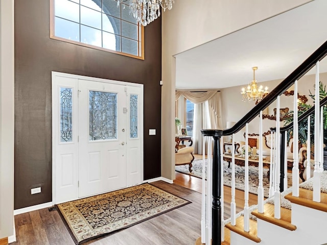 entrance foyer featuring a notable chandelier, stairway, a high ceiling, wood finished floors, and baseboards