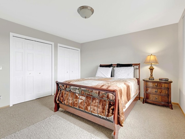 carpeted bedroom with multiple closets and baseboards