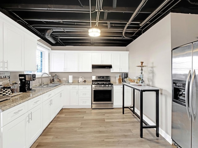 kitchen featuring under cabinet range hood, stainless steel appliances, a sink, white cabinets, and light wood-type flooring