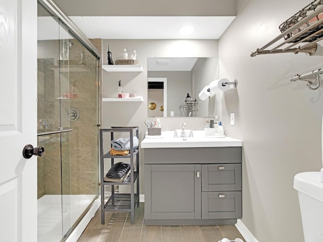 bathroom with a stall shower, baseboards, toilet, wood tiled floor, and vanity