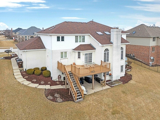 rear view of property with a deck, a shingled roof, stairs, a yard, and a chimney