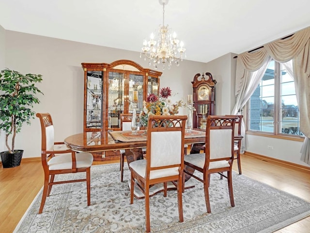 dining space with baseboards, a chandelier, and wood finished floors