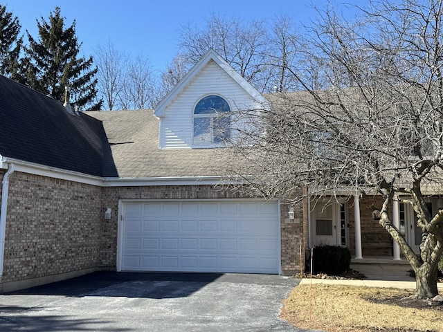 view of front of property with an attached garage, roof with shingles, aphalt driveway, and brick siding