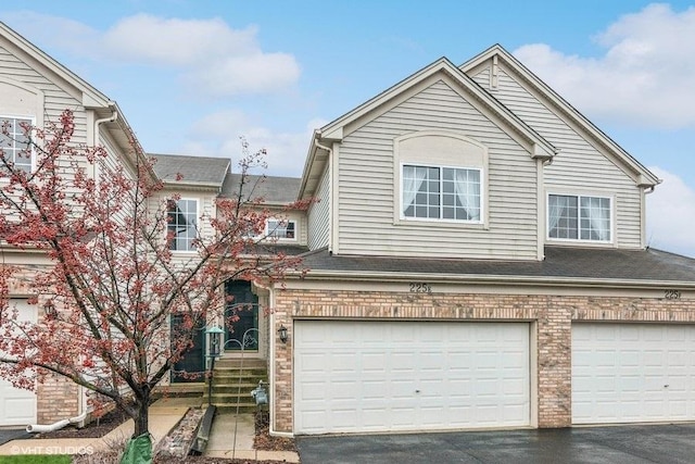 view of front of house featuring driveway, brick siding, and an attached garage