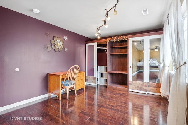 home office featuring track lighting, wood finished floors, visible vents, and baseboards