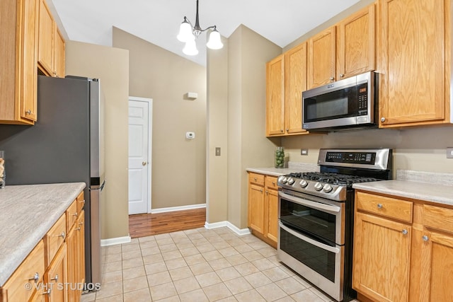 kitchen featuring light tile patterned floors, baseboards, appliances with stainless steel finishes, and light countertops