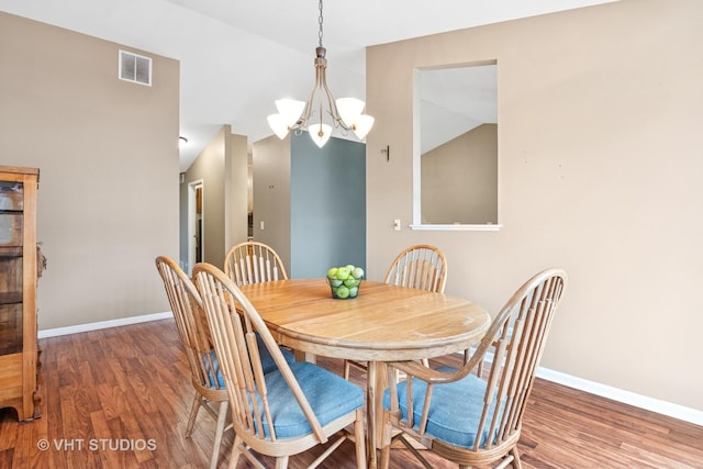 dining space with baseboards, visible vents, a notable chandelier, and wood finished floors