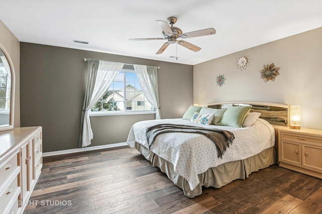 bedroom featuring baseboards, visible vents, dark wood finished floors, and a ceiling fan