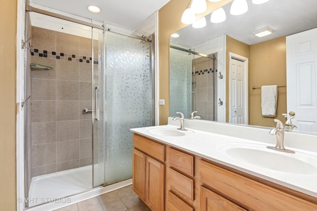 bathroom featuring double vanity, a stall shower, tile patterned flooring, and a sink