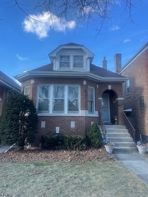 view of front of house featuring a chimney, a front lawn, and brick siding