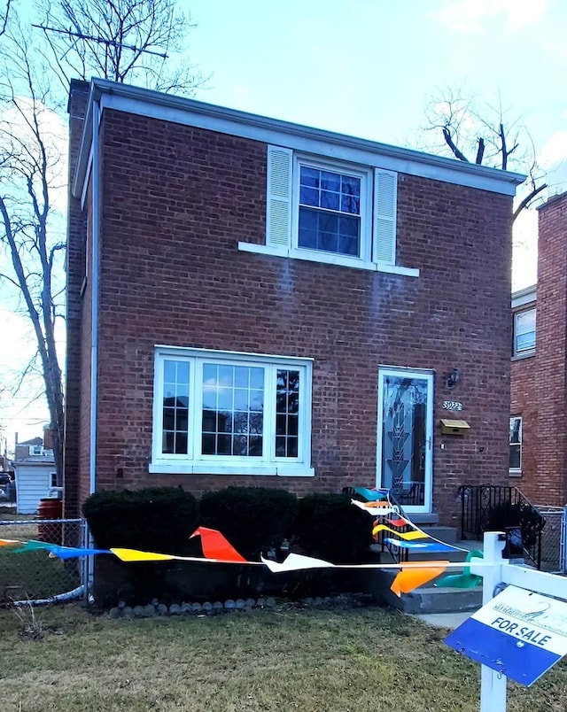 back of property with brick siding, a lawn, and fence