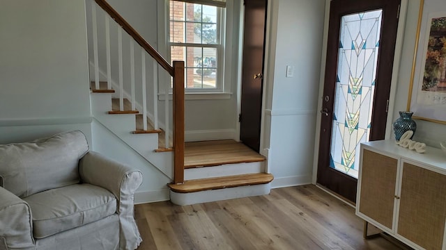 entryway featuring light wood-style floors, baseboards, and stairway