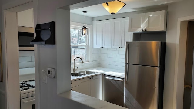 kitchen with stainless steel appliances, tasteful backsplash, a sink, and white cabinetry