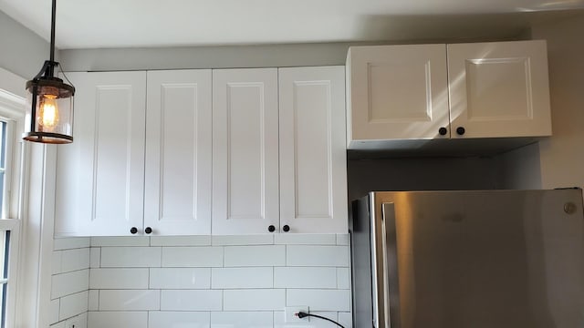 kitchen with white cabinetry, decorative light fixtures, and freestanding refrigerator