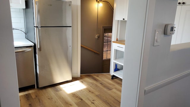 kitchen with light countertops, appliances with stainless steel finishes, light wood-type flooring, and white cabinetry