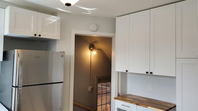 kitchen with butcher block countertops, white cabinets, and freestanding refrigerator