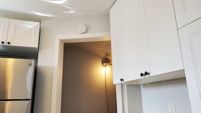 interior details with freestanding refrigerator and white cabinetry