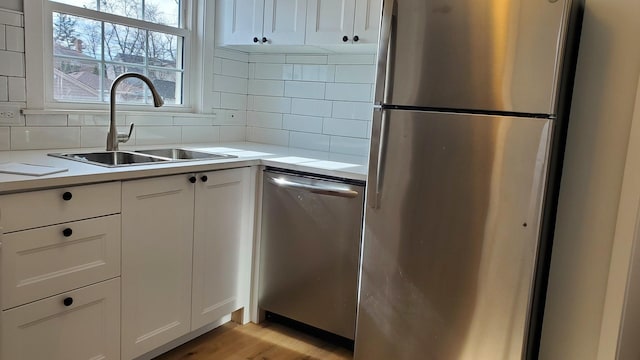 kitchen with light countertops, appliances with stainless steel finishes, a sink, and tasteful backsplash