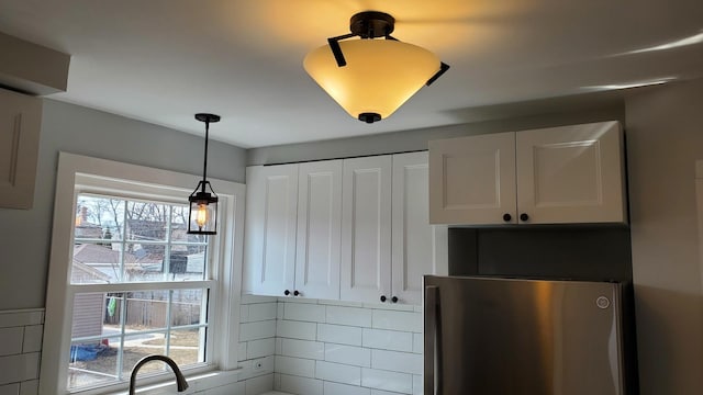 kitchen featuring hanging light fixtures, decorative backsplash, freestanding refrigerator, and white cabinets