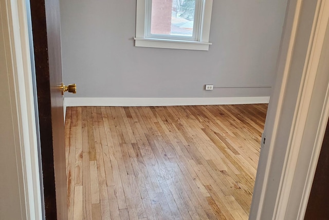 spare room featuring hardwood / wood-style flooring and baseboards