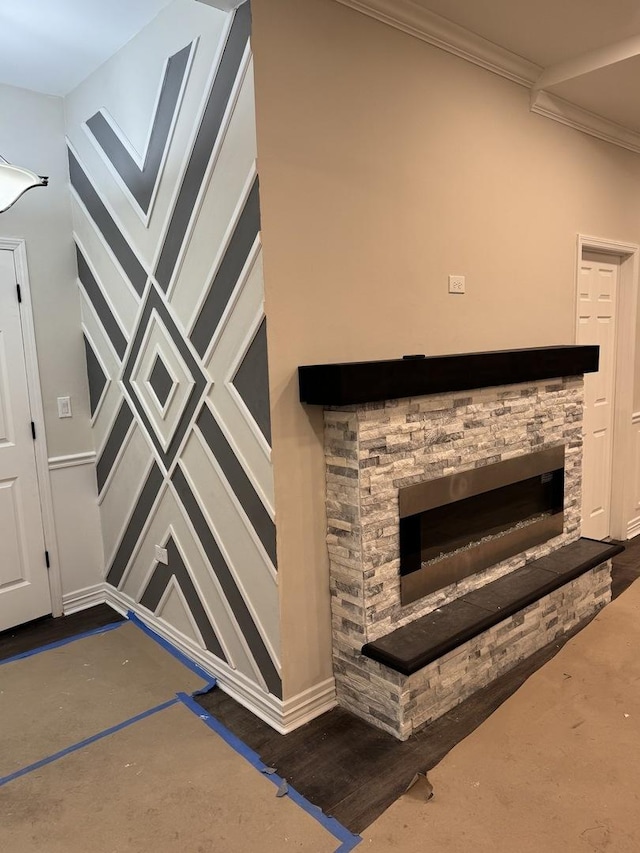 room details featuring ornamental molding, a stone fireplace, and wood finished floors