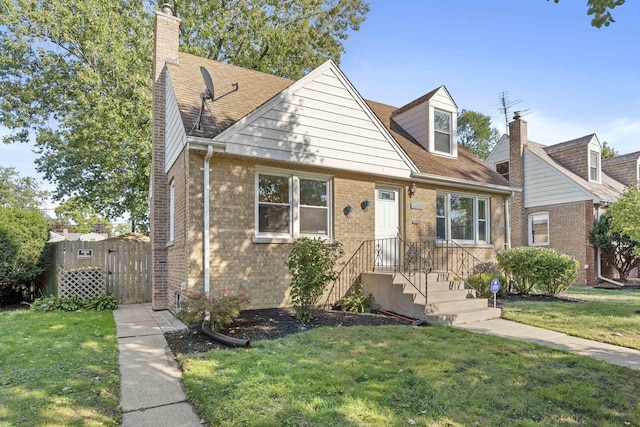 view of front of property with brick siding, a shingled roof, a chimney, a gate, and a front yard