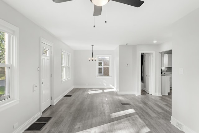 unfurnished living room with a healthy amount of sunlight, a sink, visible vents, and wood finished floors