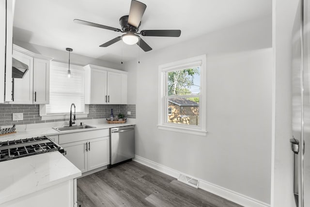 kitchen with tasteful backsplash, baseboards, dark wood-style flooring, stainless steel dishwasher, and a sink