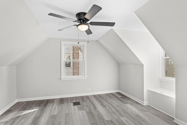 bonus room with lofted ceiling, visible vents, baseboards, and wood finished floors