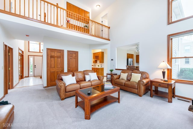 living area featuring baseboards, a high ceiling, visible vents, and light colored carpet