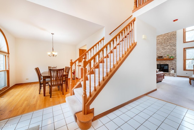 staircase featuring a chandelier, a fireplace, tile patterned flooring, and baseboards