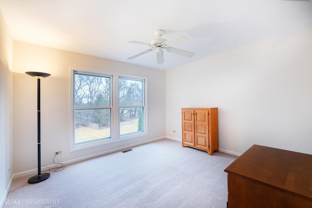 interior space featuring a ceiling fan, visible vents, light carpet, and baseboards