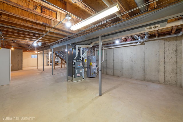 unfinished basement with water heater, visible vents, and heating unit