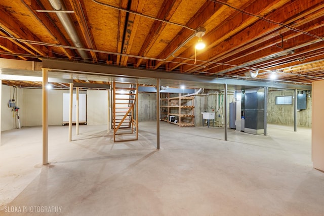 unfinished basement featuring gas water heater, electric panel, a sink, and heating unit