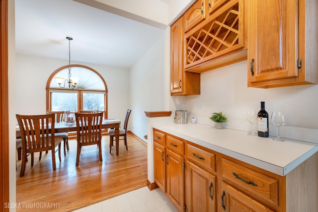 kitchen with a chandelier, brown cabinetry, light countertops, and decorative light fixtures