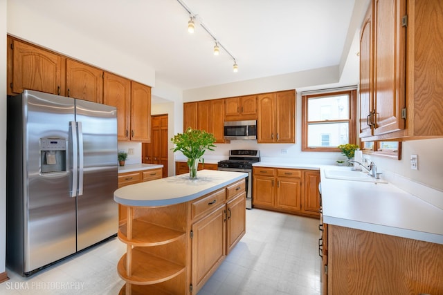 kitchen with a kitchen island, a sink, light countertops, appliances with stainless steel finishes, and light floors