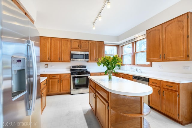 kitchen featuring appliances with stainless steel finishes, brown cabinetry, light countertops, and light floors