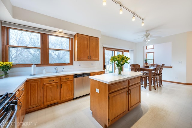 kitchen featuring light floors, stainless steel dishwasher, a sink, and gas range