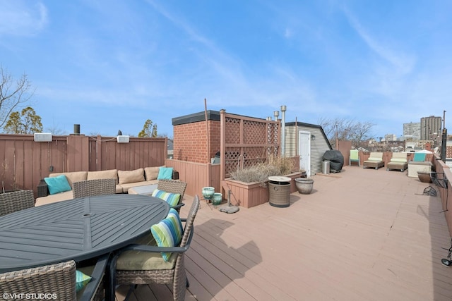 deck featuring a storage unit, outdoor dining area, and an outdoor structure