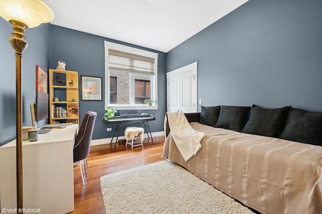 bedroom with a closet, wood finished floors, and baseboards