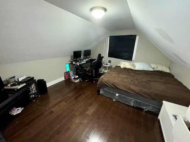 bedroom with baseboards, vaulted ceiling, and wood finished floors