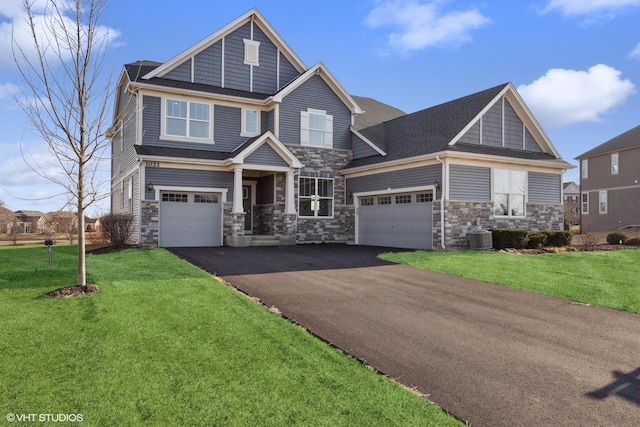 craftsman inspired home with aphalt driveway, central AC, a front yard, stone siding, and an attached garage