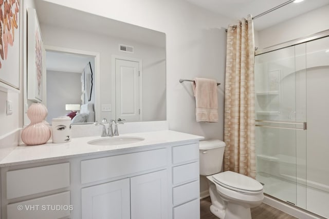 full bathroom with visible vents, toilet, wood finished floors, a shower stall, and vanity