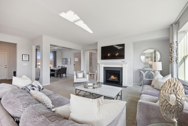 living room featuring baseboards, light carpet, and a fireplace with flush hearth