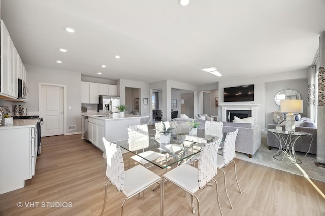 dining room with recessed lighting, visible vents, a fireplace, and light wood finished floors