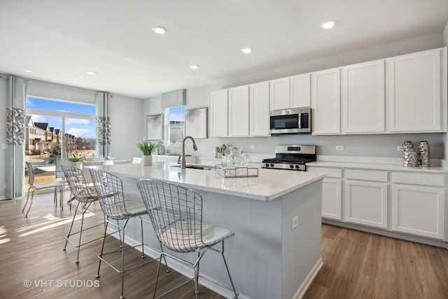 kitchen featuring a breakfast bar area, light wood-type flooring, an island with sink, appliances with stainless steel finishes, and a sink