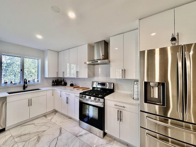 kitchen with marble finish floor, stainless steel appliances, light countertops, a sink, and wall chimney range hood