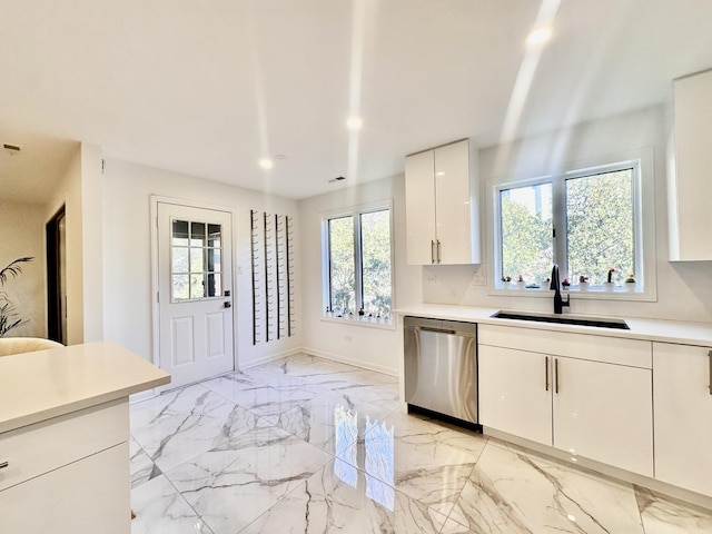 kitchen with marble finish floor, light countertops, stainless steel dishwasher, white cabinetry, and a sink